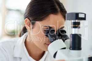 Things are a lot different under the lens. a young scientist using a microscope in a lab.