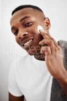 I look good because I take care of myself. a handsome young man applying moisturizer to his face at home.