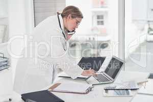 Let me just double-check that on my laptop. an attractive young female doctor typing on a laptop while taking a phonecall in her office.