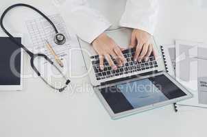 Wireless technology has become the centre of doctoring. High angle shot of an unrecognizable female doctor using a laptop while working in her office.