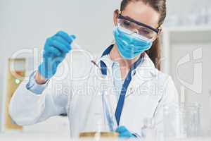 I have to ad this very carefully. an unrecognizable young female scientist wearing protective face gear while conducting experiments inside of a laboratory.
