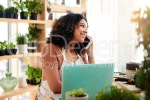 I can have that ready for you within the hour. an attractive young female botanist making a phonecall while working on a laptop in her florist.