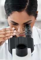 What resolves all scientific mysteries The microscope of course. Closeup shot of an attractive young female scientist looking through a microscope while working in a laboratory.