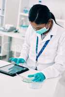 Shes found the perfect app to guide her through her experiment. an attractive young female scientist using a digital tablet while working in a laboratory.