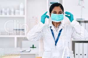 Safety is every scientists priority. an attractive young female scientist putting on a mask while working in a laboratory.