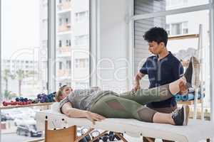 Fluent movement is essential to recovery. a young physiotherapist doing leg exercises with her patient inside her office at a clinic.