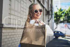 Follow me, Ive got a couple more shops to visit. Cropped portrait of an attractive young woman smiling while holding shopping bags in the city during the day.