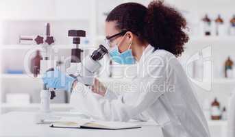 Conducting another careful test. a young scientist using a microscope in a lab.