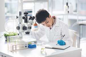 Recording of results is very important in science. an attractive young female scientist making notes while working with a microscope and plants in a laboratory.
