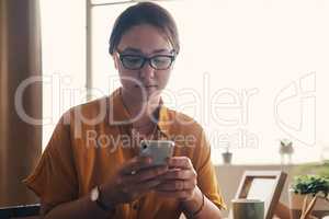 Focus and discipline gets it done. a young woman using a smartphone while working from home.