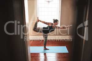 The essence of yoga is all about balance. a young woman practising yoga at home.