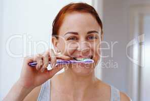 Fresh breath never goes out of style. Portrait of an attractive young woman brushing her teeth inside her bathroom at home.