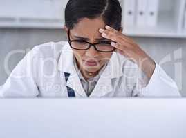 The answers are becoming hard to find. an attractive young female scientist looking stressed while working in her laboratory.