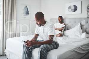 He used to hold me like that. a young man ignoring his wife while using a smartphone in the bedroom at home.