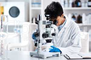 Science broadens perspectives. a young scientist using a microscope in a lab.