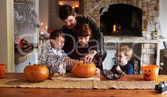 Things are getting really spooky right now. an adorable young family carving out pumpkins and celebrating halloween together at home.