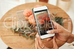 Picture perfect. an unrecognizable businesswoman using her cellphone to take pictures of cupcakes for her blog.