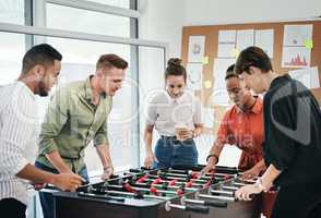 We were friends before we became colleagues. a diverse group of businesspeople standing together and bonding over a game of foosball in the office.