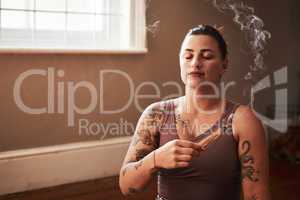 Meditation carries me more calmly through my day. a young woman burning a palo santo stick at home.