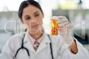 Creating a cure thatll work. a young medical scientist holding a bottle of pills in a lab.