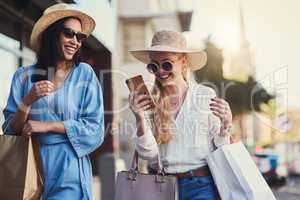 Girl I think my crush just responded. an attractive young woman smiling at her smartphone while walking with her best friend during a shopping spree in the city.