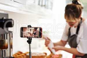 Heres another video on frosting. a woman being recorded on a cellphone while baking in her kitchen.