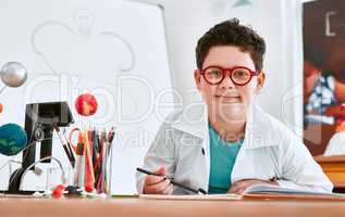 Science is my favorite subject at school. Portrait of an adorable young school boy writing notes in his note book in science class at school.