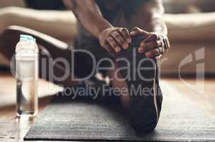 Good habits lead to the best outcomes. Closeup shot of an unrecognisable man stretching his legs while exercising at home.