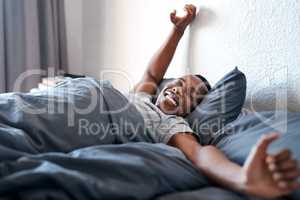 Rise and shine. a handsome young man lying in bed alone and stretching during a day off at home.
