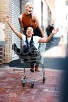 Friends make trolleys fun. Full length shot of two cheerful young girlfriends having fun with a shopping cart outdoors during the day.