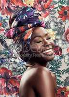That glow that comes from your soul. Studio shot of a beautiful young woman wearing a traditional African head wrap against a floral background.