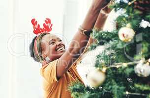 Nothing gets you in the spirit like decorating the tree. an attractive young businesswoman decorating a Christmas tree in her office at work.