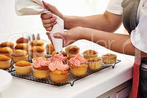 You need some sweetness in your life. an unrecognizable woman piping icing onto her cupcakes.