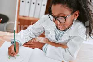 School is cool and thats a fact. an adorable young school girl drawing a diagram in her exercise book in science class at school.