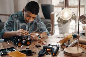 We are all born to create and do the extraordinary. a handsome young boy building a robotic toy car at home.