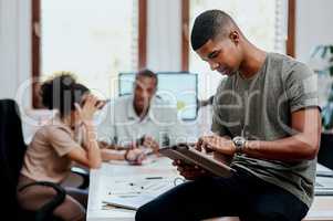 The perfect tool for a modern manager. a young businessman using a digital tablet during a meeting in a modern office.