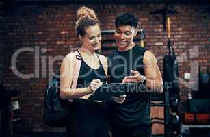 Sign up for our new fitness program. a sporty young woman talking to a fitness trainer at the gym.