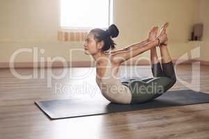 Stretch out of your comfort zone. Full length shot of an attractive young woman stretching and working out in a yoga studio.