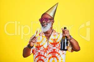 I came here to party. a funky and cheerful senior man celebrating and drinking champagne in studio against a yellow background.
