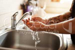 Washing your hands is the way to good health. a woman washing her hands at the kitchen sink.