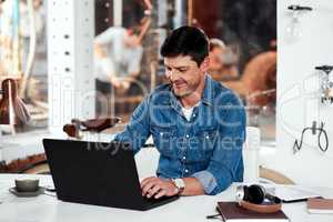 Everything is working in my favor today. a handsome young businessman working on a laptop in an office inside his workshop.