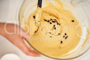 Chocolate chips fixes everything. an unrecognizable woman mixing batter in a glass bowl.