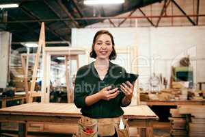 We advertise every piece we finish online. a female carpenter using a digital tablet in her workshop.