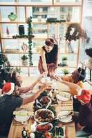 Heres to many more Christmases together. High angle shot of a group of cheerful young friends making a toast while dining together at Christmas.