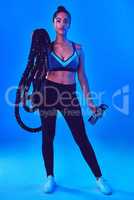 The greatest strength always comes from within. Full length shot of an attractive young sportswoman posing carrying battle ropes against a blue background.