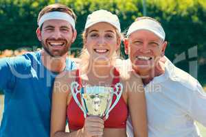 Post victory picture is necessary. Cropped portrait of a group of sportspeople standing together and holding a trophy after winning a tennis match.