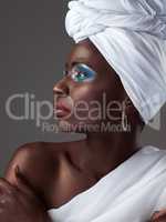 Its so much more than just a head wrap. Studio shot of an attractive young woman posing in traditional African attire against a grey background.