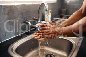 First rule of using the kitchen Cleanliness. an unrecognizable man washing his hands in the kitchen sink at home.