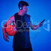 The right playlist will get me in the groove. Blue filtered shot of a sportsman wearing headphones while holding a basketball.