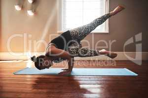 Building a fit and flexible body through yoga. a young woman practising yoga at home.